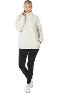 Woman wearing a cream-colored fleece jacket and black leggings on a white background