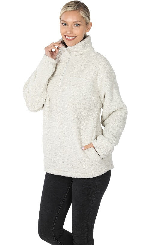 Woman wearing a cream-colored fleece pullover on a white background