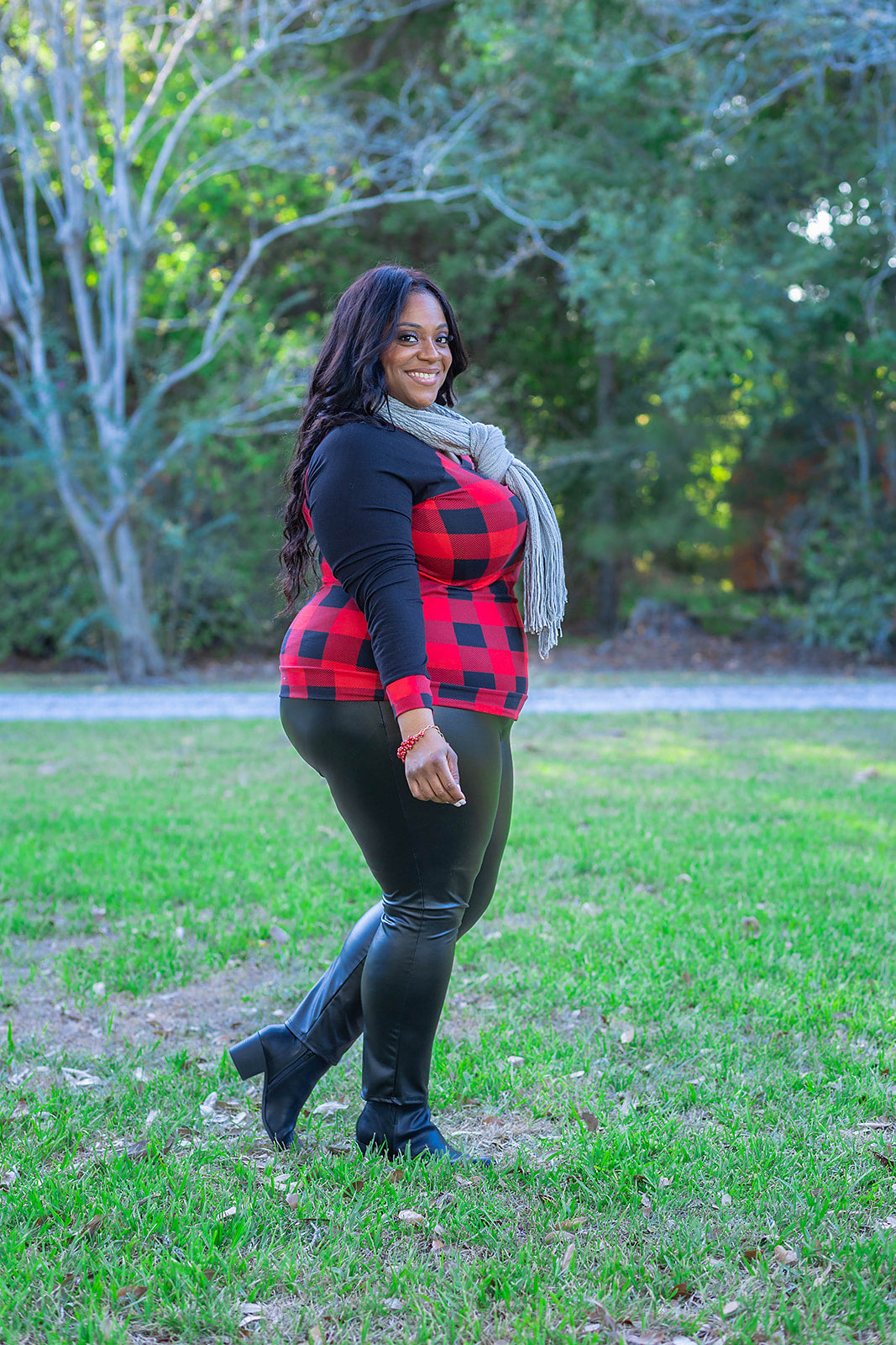 Raglan sleeve contrasting long sleeve top with red and black buffalo check print. This image features a gorgeous, plus size woman over 40 rocking this gingham print long sleeve crew neck top with a grey fringe scarf, red geometric earrings, and faux leather leggings with a pair of faux leather booties from the fall collection at Jolie Vaughan Boutique.